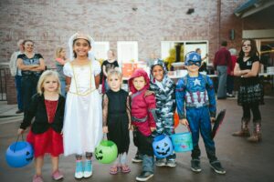 Children in Halloween costumes holding a jack-o’-lantern